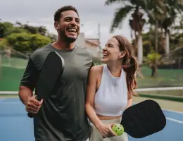 two young adults standing on a pickleball court